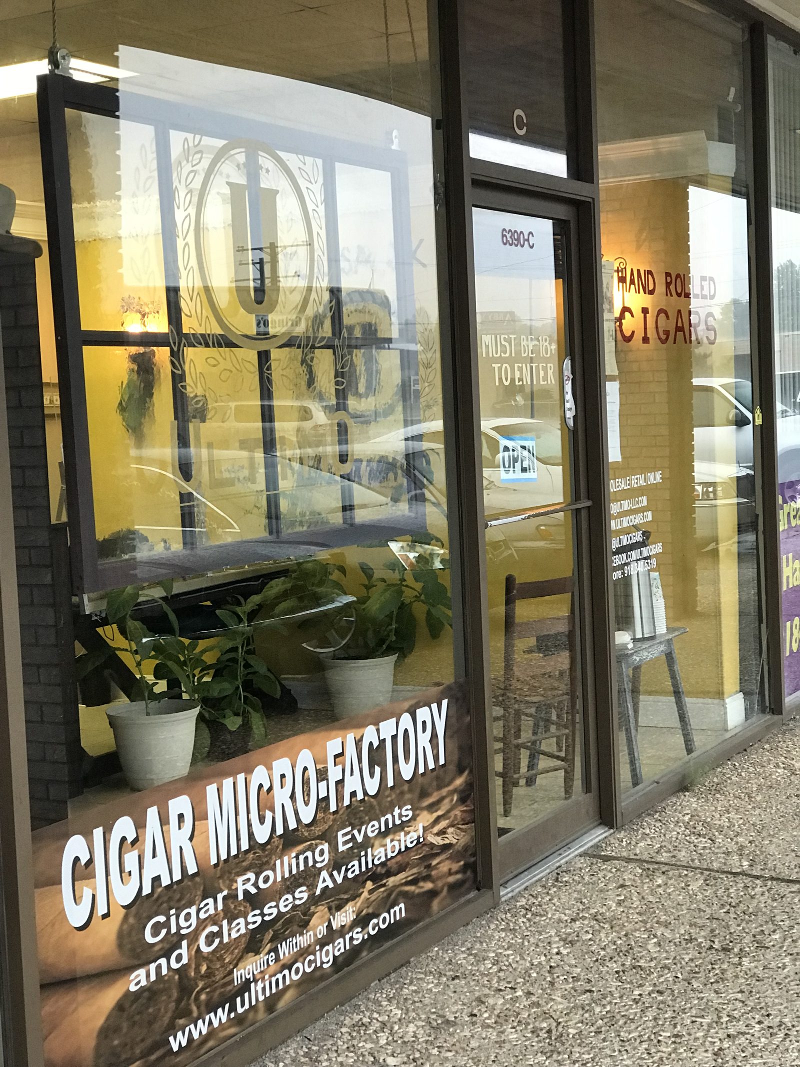 Glass entrance of Ultimo Cigars with window lettering reading Cigar Micro-Factory